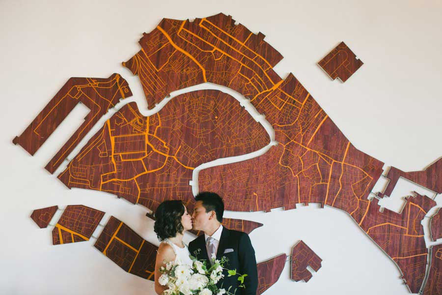 Bride and groom in front of wood artwork | One Love Photography