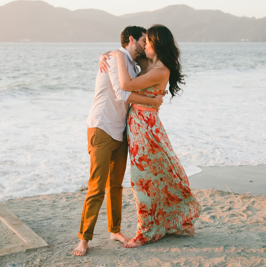 A couple kisses on the beach in San Francisco at sunset.