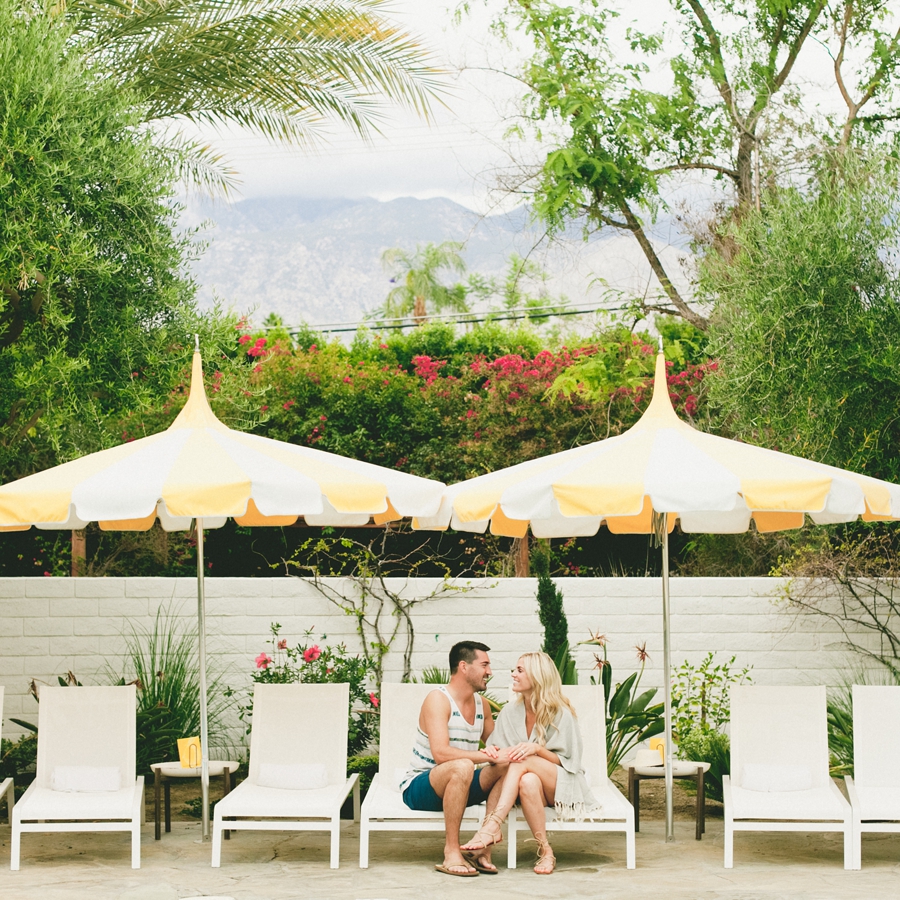 A pool party engagement session with yellow sun umbrellas.