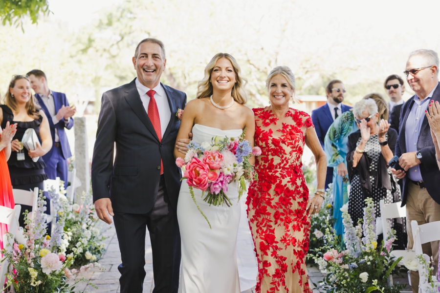 A father and mother escort a bride down the wedding aisle