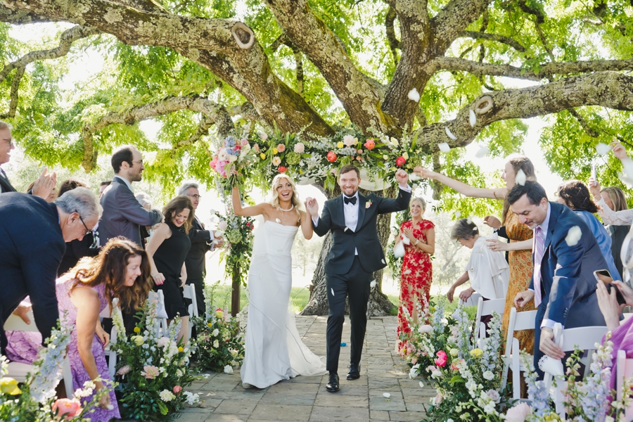 A bride and groom raise their hands celebrating