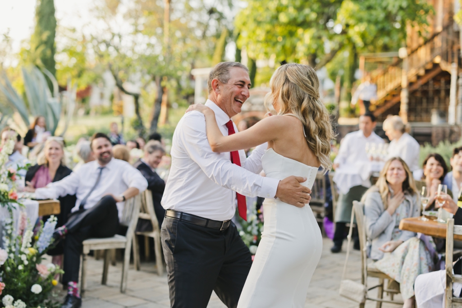 A father dances and smiles outdoors with his daughter at SSS Ranch