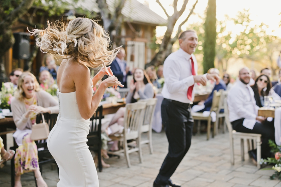 A brides hair blows in the air while she dances outside with an older man at SSS Ranch in Napa